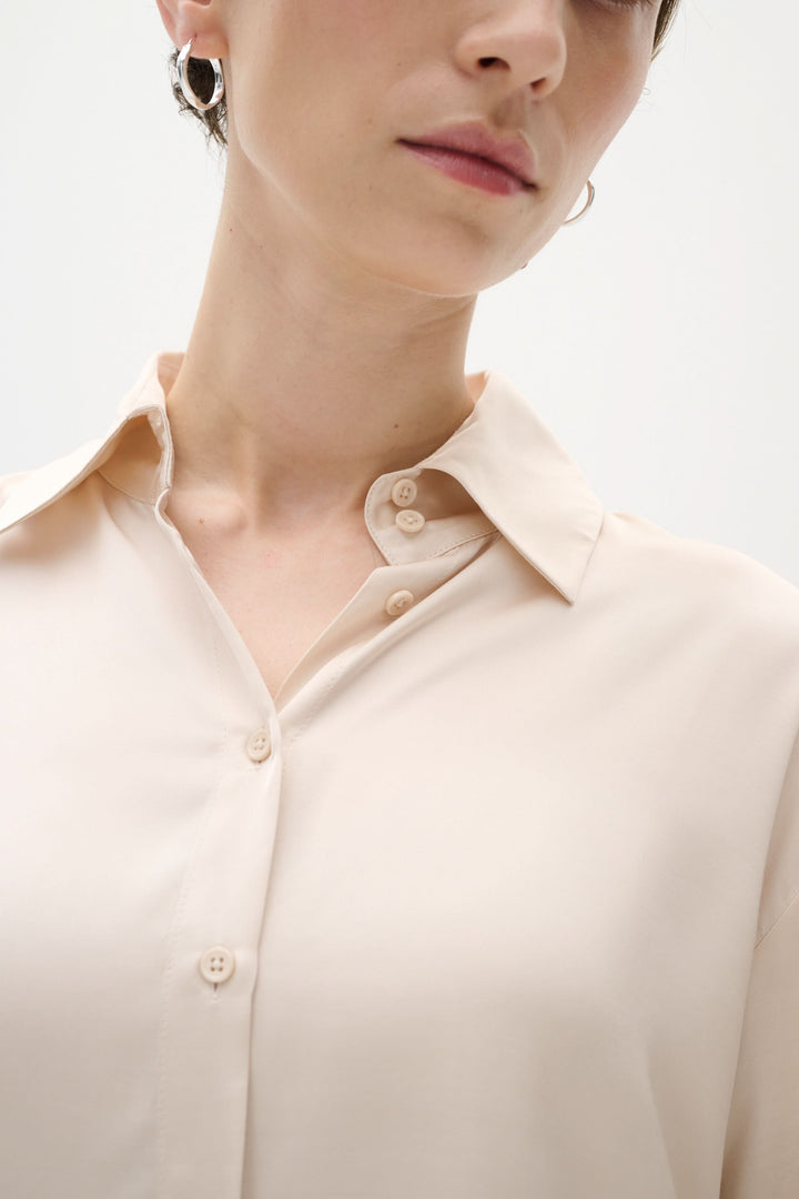 Chemise Pauline satinée, ample et chic, avec col de chemise et boutons sur le devant, portée par un modèle.
