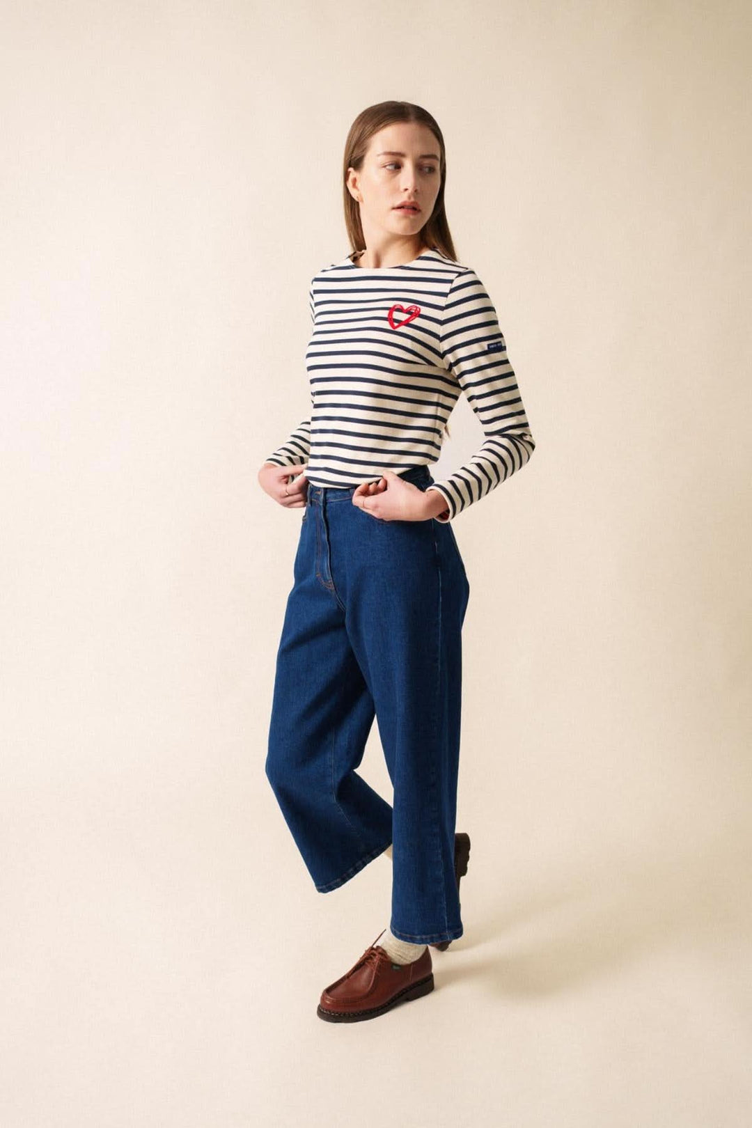 Chandail MERID'AMOUR marinière rayée avec motif cœur en velours, porté avec pantalon bleu, style casual-chic.