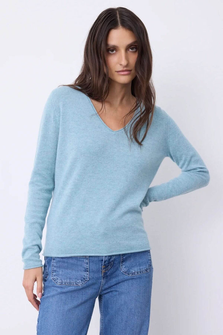 Chandail à manches longues bleu clair avec encolure en V, porté avec un jean, style élégant et confortable.