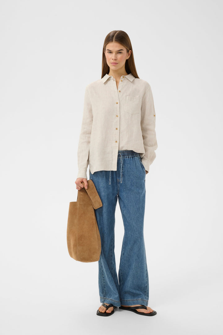 Jeans Sophina taille élastique jambe large avec une chemise beige, poches latérales et tissu denim souple.