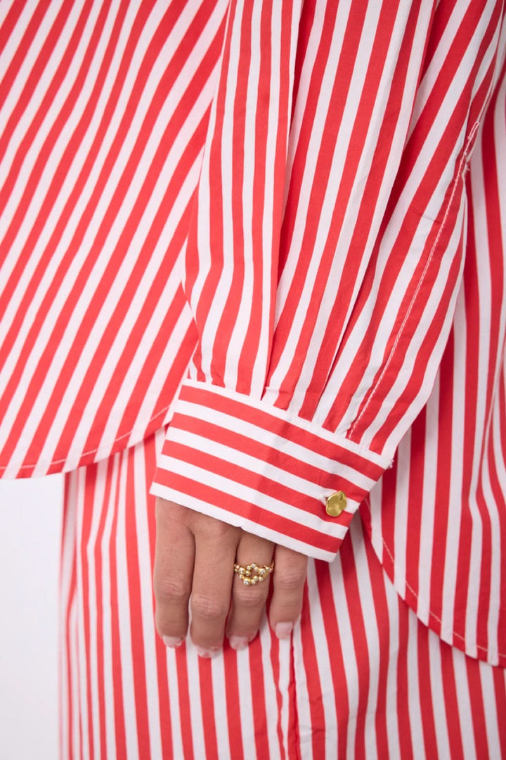 Gros plan sur la manche de la Chemise rayée Althea coupe fluide classique, avec un motif rayé vertical rouge et blanc.