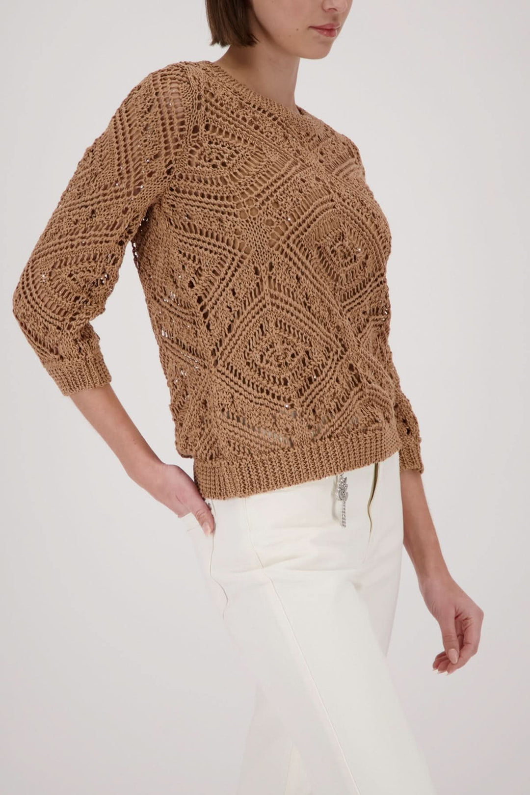 Modele portant un tricot ajouré à motifs, texture respirante et légère, idéal pour un look moderne et féminin.