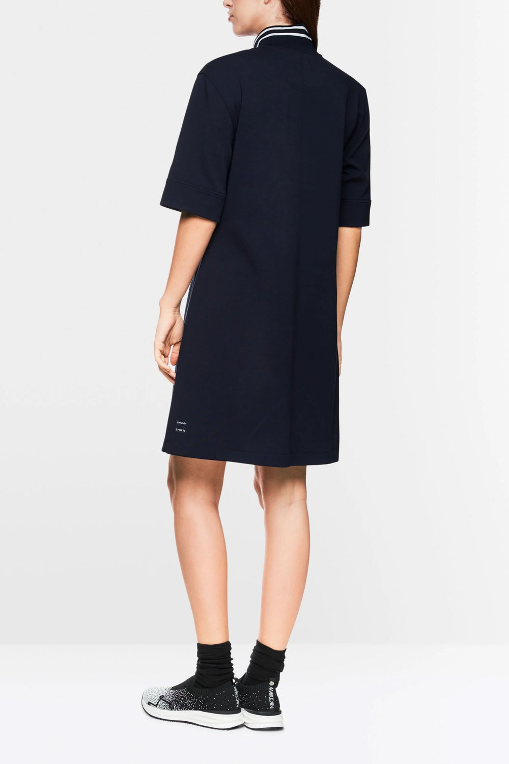 Robe courte sportive chic, col montant rayé, fermeture zippée, portée avec des baskets pour un look urbain.