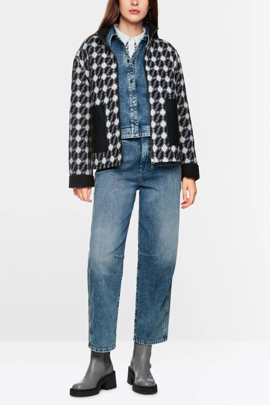 Veste à motif graphique en noir et blanc portée avec un ensemble en denim et des bottes grises.