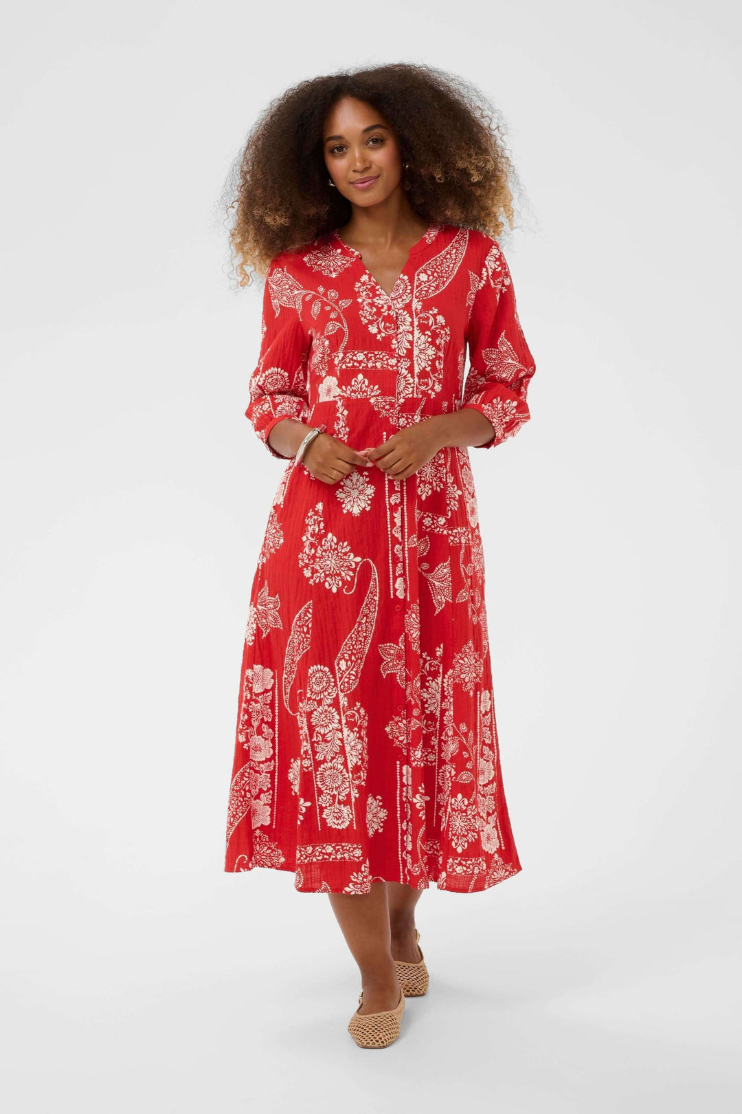 Femme portant la Robe Bia midi imprimée à manches trois-quarts avec un élégant motif rouge et blanc.