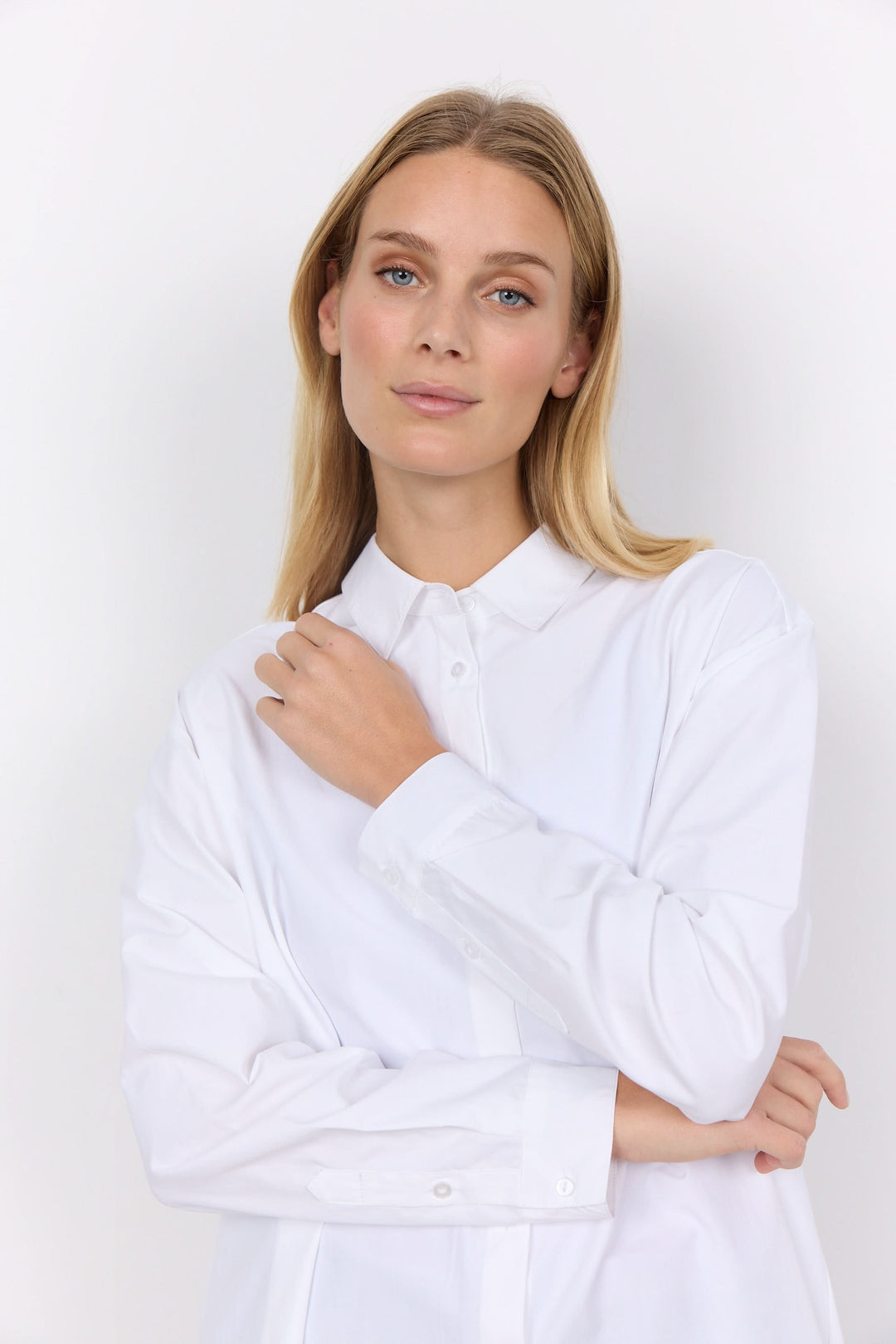 Chemise décontractée blanche, élégante et confortable, portée par un mannequin féminin avec un col classique.
