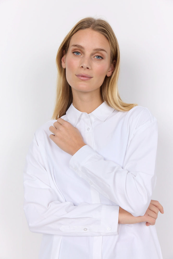 Chemise décontractée blanche, élégante et confortable, portée par un mannequin féminin avec un col classique.