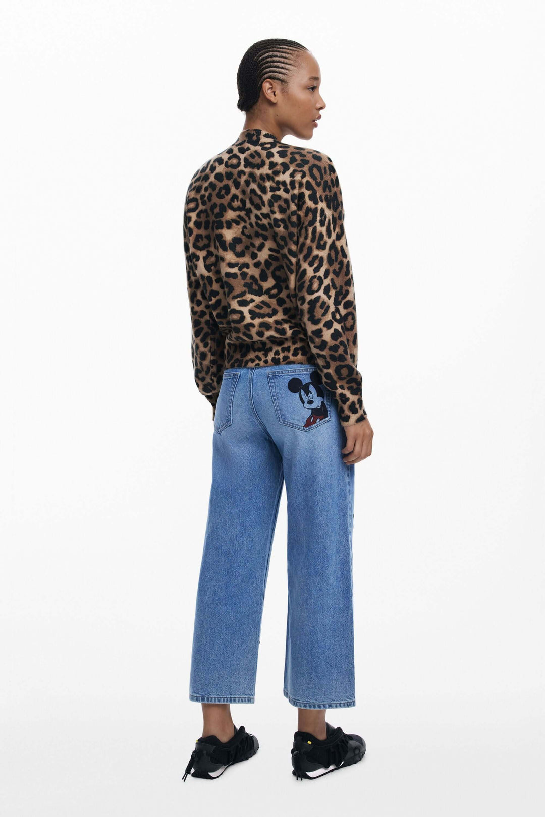 Femme portant un chandail animalier avec un portrait stylisé de Minnie Mouse, associé à un jean bleu clair.