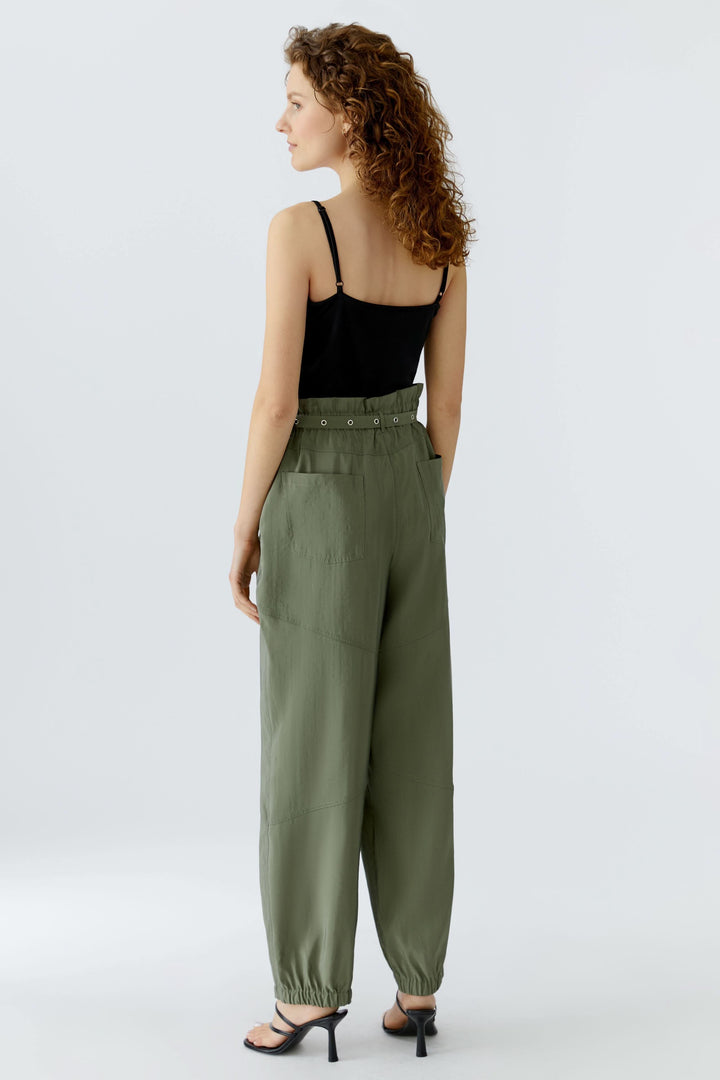 Femme portant un pantalon jogger ceinturé vert avec taille élastique et ceinture intégrée, vue de dos, sur fond blanc.
