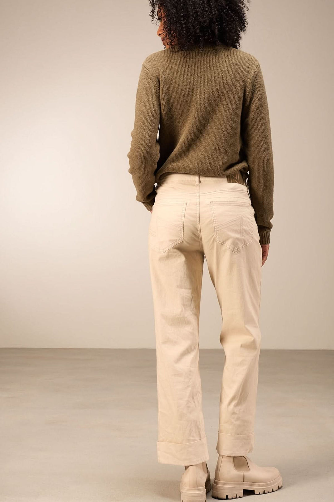 Pantalon droit beige avec taille mi-haute, porté avec un chandail à manches longues et bottines, vue arrière.