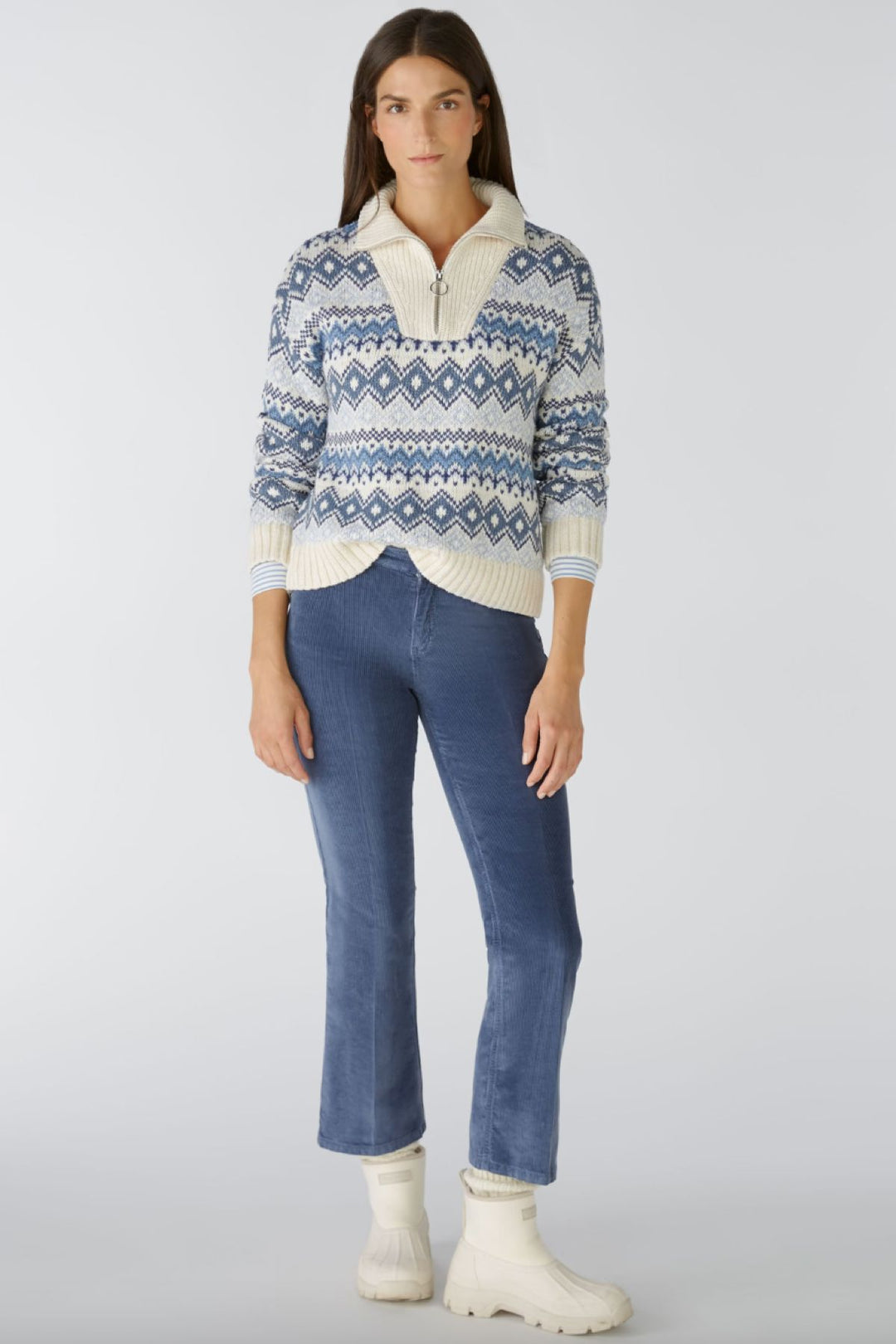 Femme portant un pull en tricot à motifs bleus et un pantalon en velours côtelé évasé, style décontracté.