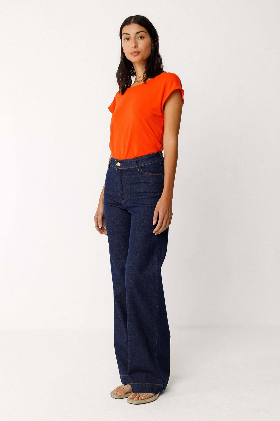 Femme portant un Jeans Ainhize coupe large taille haute, avec un t-shirt orange, offrant une silhouette moderne et élancée.