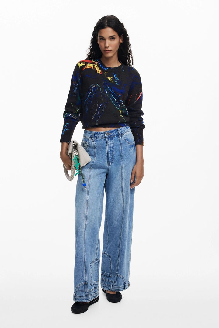 Chandail artistique abstrait à col rond avec jean large, ajoutant une touche créative et colorée à la tenue.