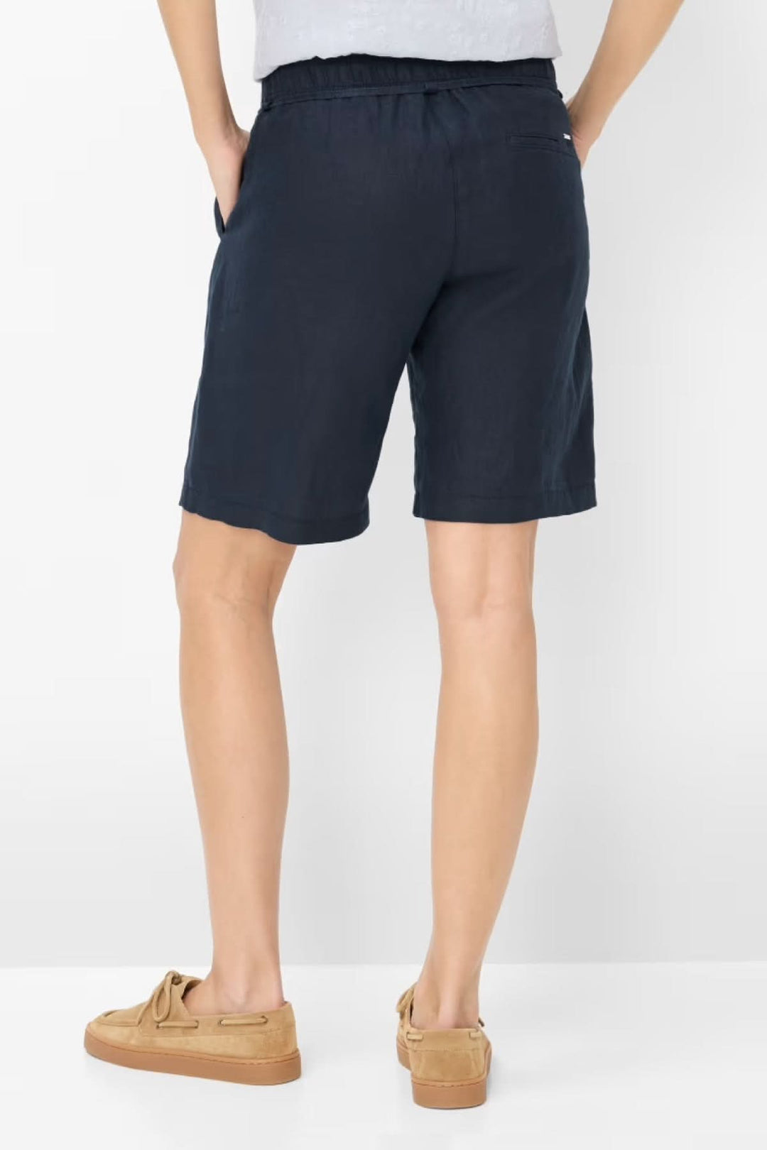 Bermudas en lin MEL B pour femme en bleu marine, coupe Relaxed Fit avec ceinture à nouer, associées à des mocassins beige.