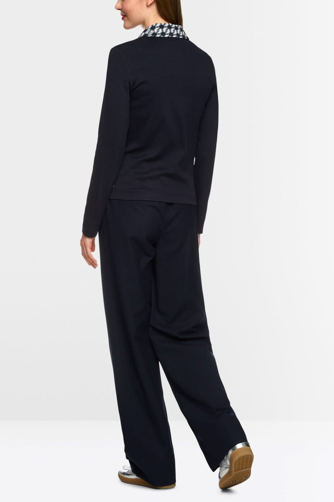 Femme vue de dos portant une veste en jersey stretch noire avec motif graphique en cubes, associée à un pantalon ample.