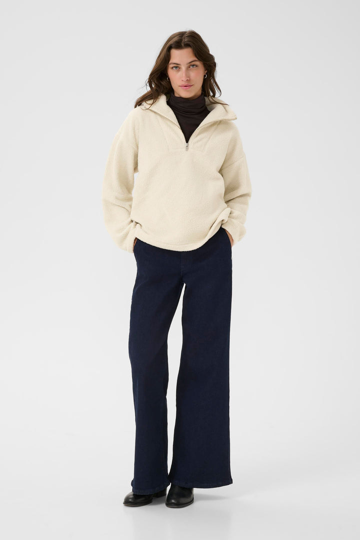 Femme portant un chandail Sirana en tissu sherpa, avec un col montant zippé et un look décontracté.