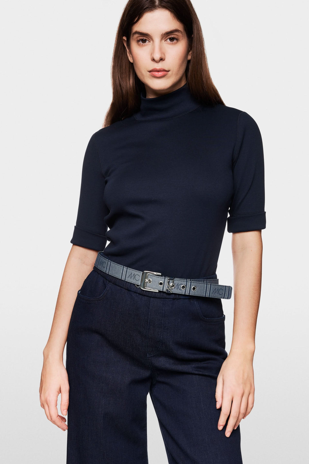 T-shirt basique col montant noir avec manches mi-longues, porté avec un pantalon et une ceinture en jean.