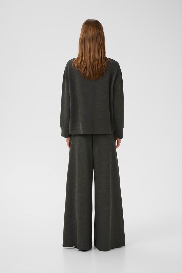 Chandail à emmanchures tombantes en tissu doux, porté avec un pantalon large, vue de dos.