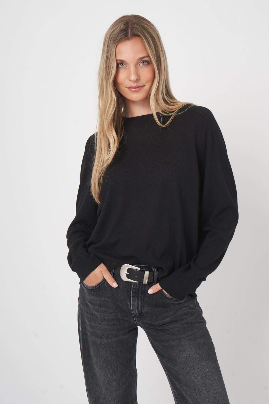 Chandail en laine noir avec coupe droite, porté avec ceinture et jean, style minimaliste et confortable.