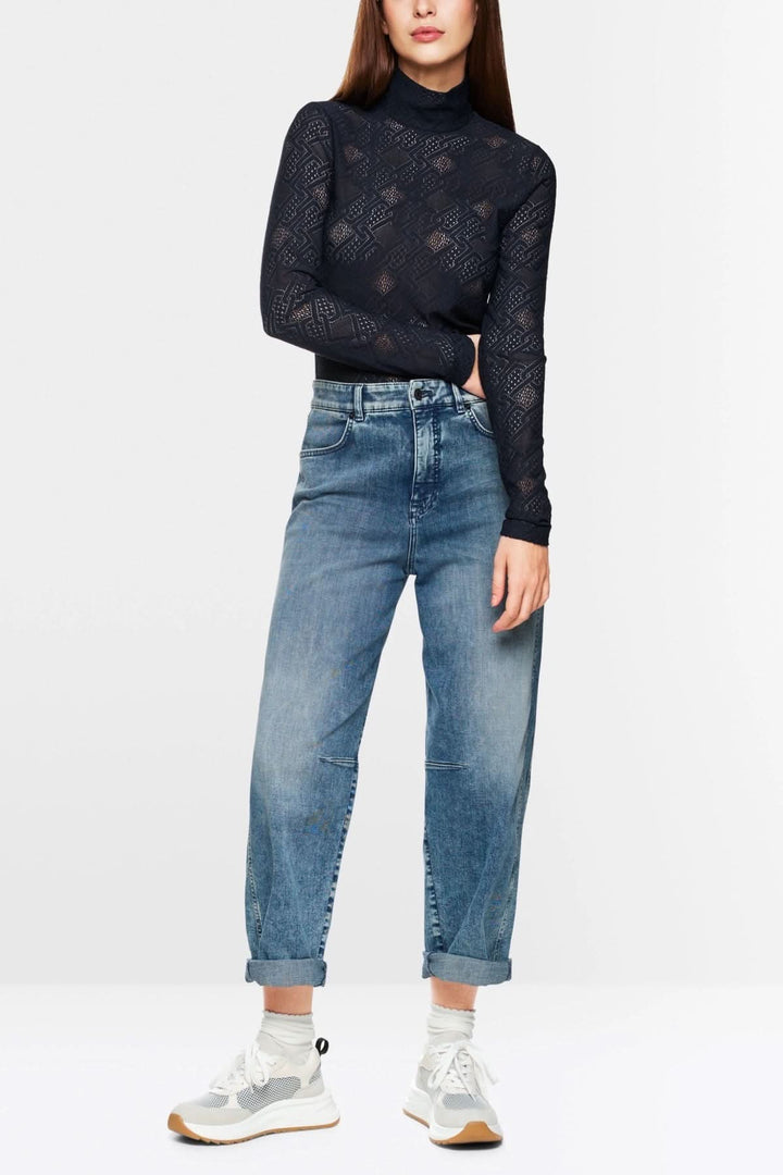 Haut en dentelle à manches longues, coupe ajustée, porté avec un jean vintage et des baskets modernes.