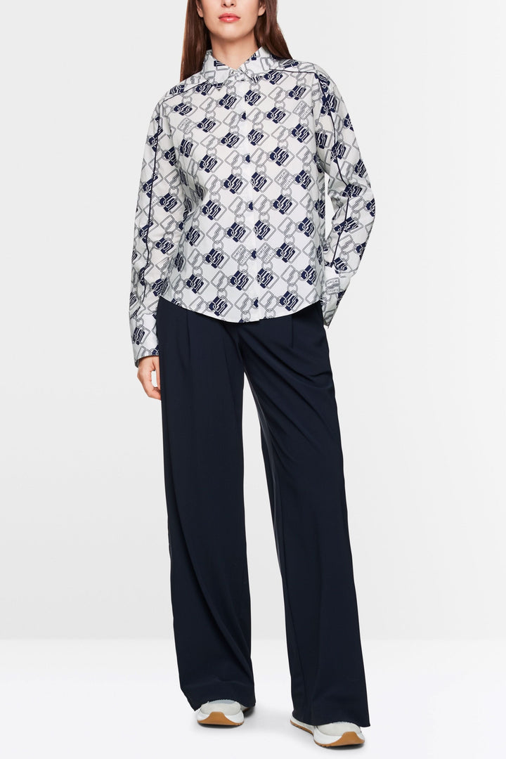 Chemise à motif chaînes avec coupe droite, portée avec un pantalon marine pour un look moderne.