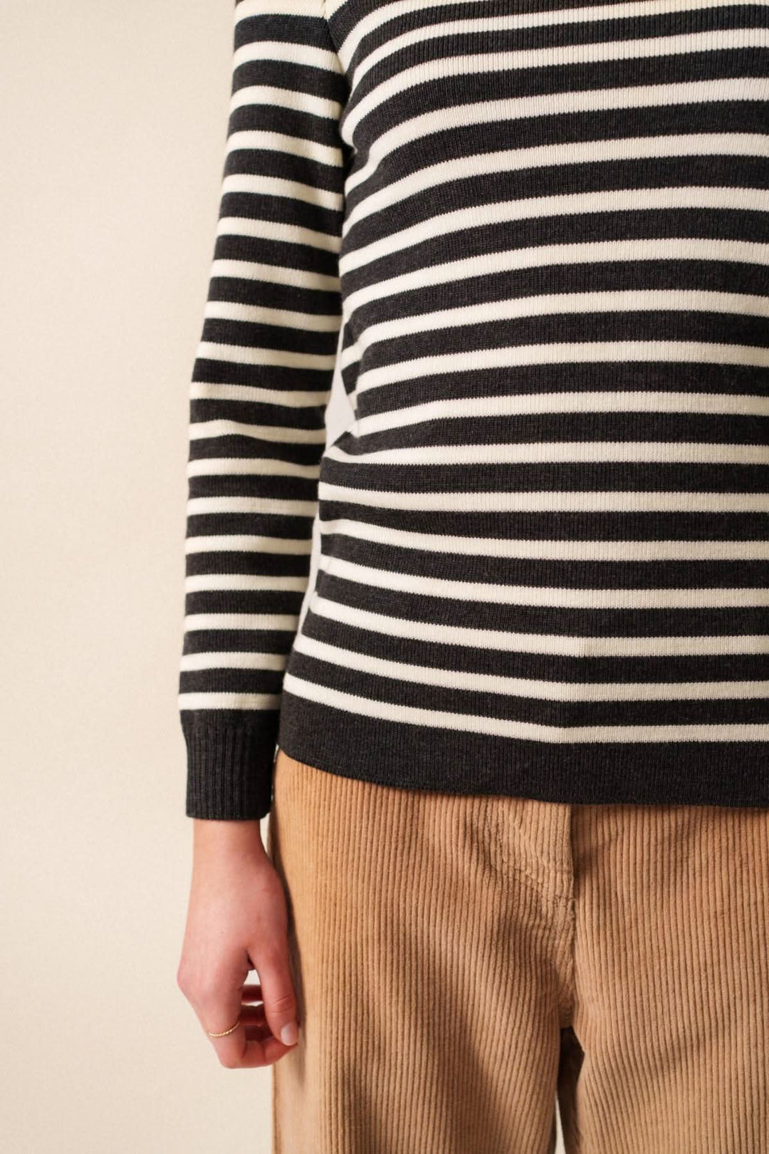 Chandail en laine mérinos à rayures noires et blanches avec pantalon en velours beige, élégant et confortable.
