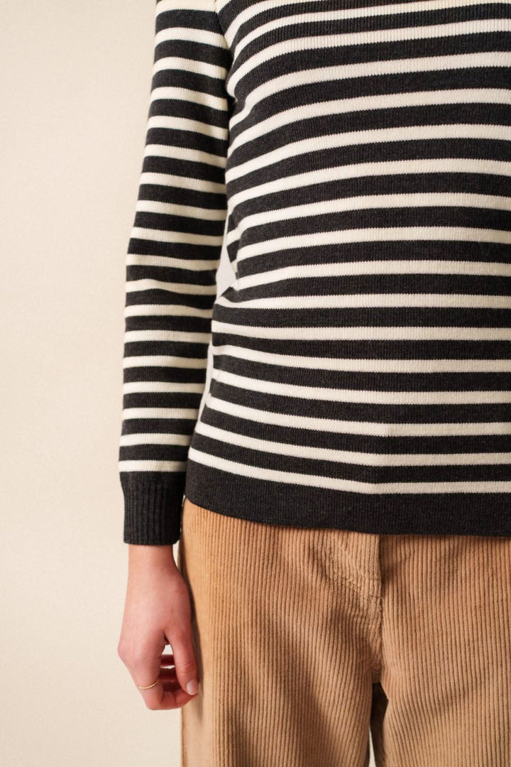 Chandail en laine mérinos à rayures noires et blanches avec pantalon en velours beige, élégant et confortable.