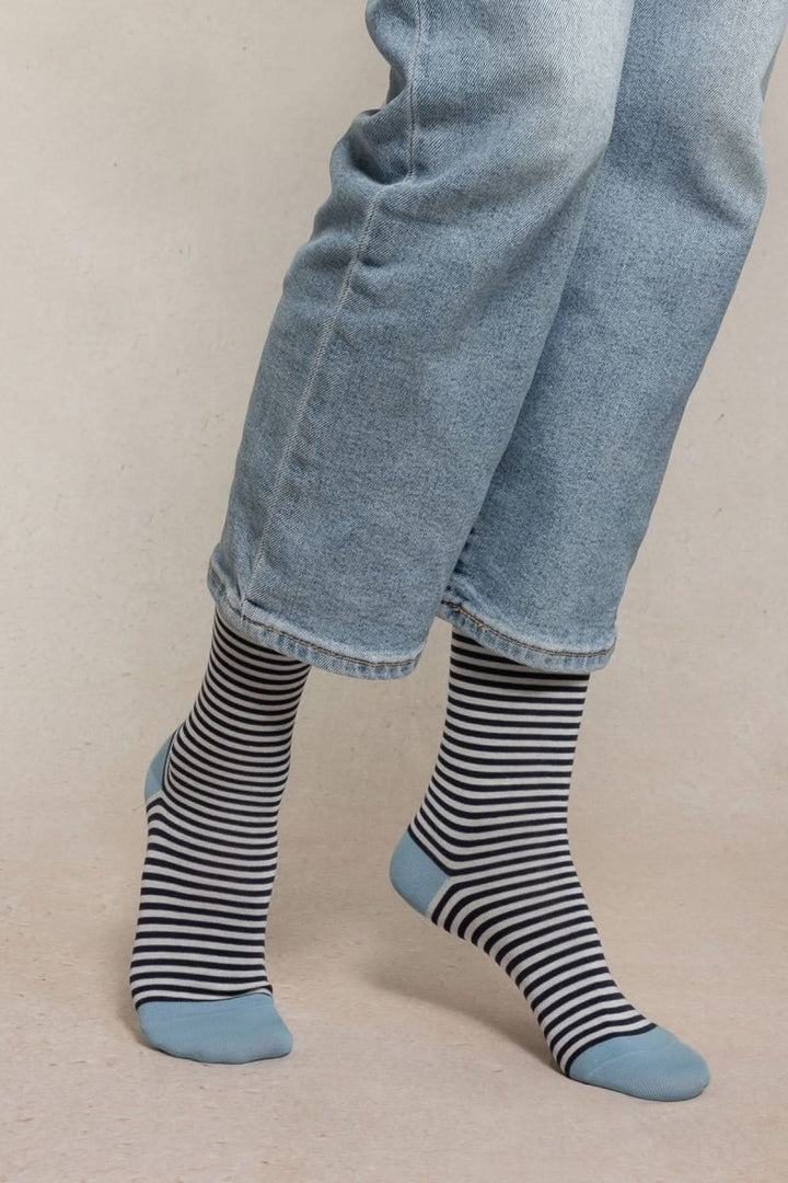Chaussettes à rayures fines en maille douce, portées avec un jean, ajoutent une touche élégante et graphique à la tenue. Modernes et confortables.