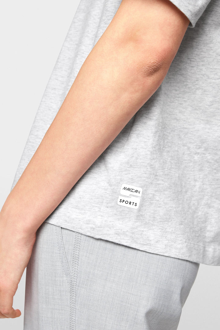 T-shirt gris léger avec étiquette de la marque Sports, offrant un look décontracté et moderne.