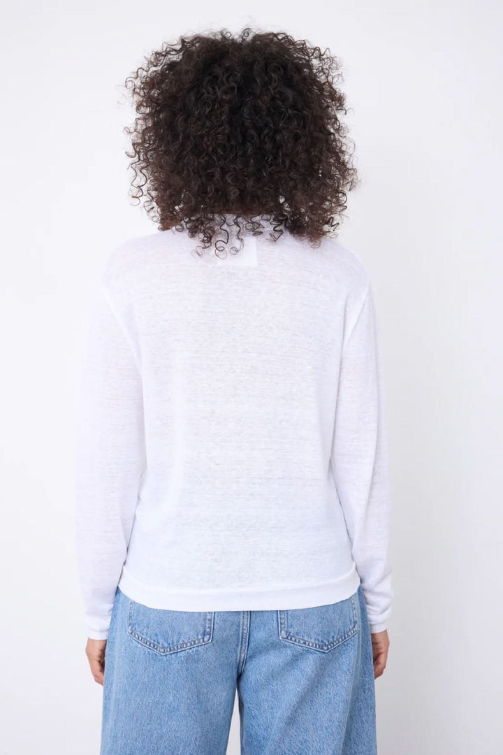 Vue arrière d'une femme portant un cardigan col v boutonné léger blanc, avec des manches longues et une coupe décontractée.