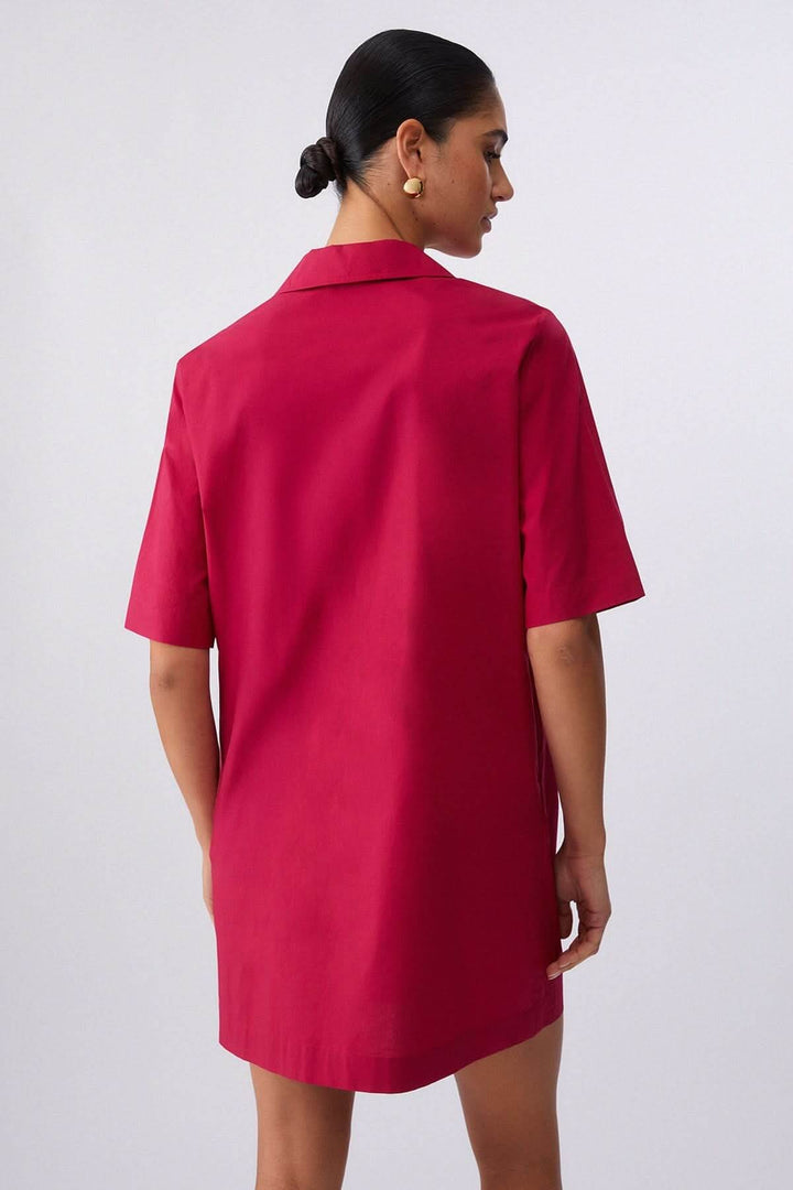 Femme portant une robe droite à col chemise lacé, vue de dos, coupe épurée et manches courtes, couleur rouge.