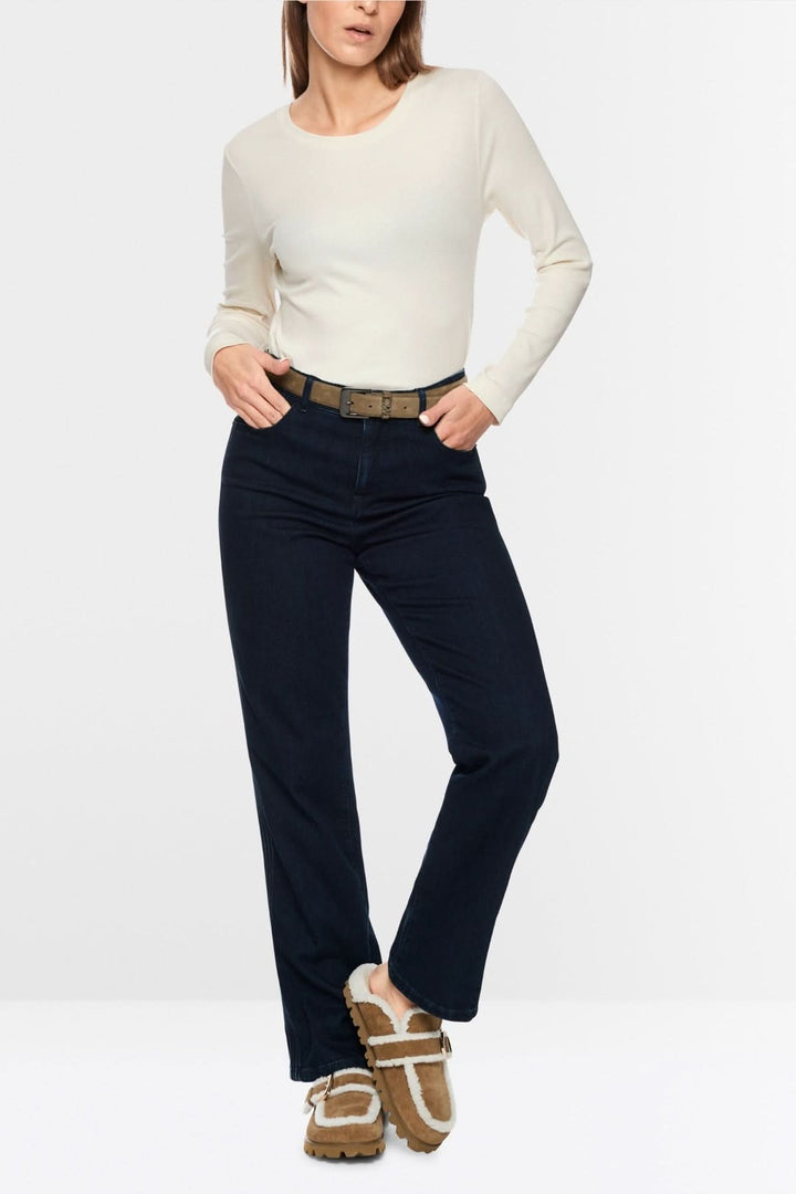 Femme portant un chandail unie à manches longues blanc avec pantalon noir, style minimaliste et chic.