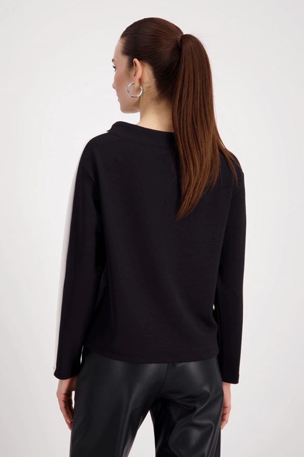 Femme portant un chandail à rayures avec col ajustable et manches longues, vue arrière. Style sport-chic moderne et confortable.