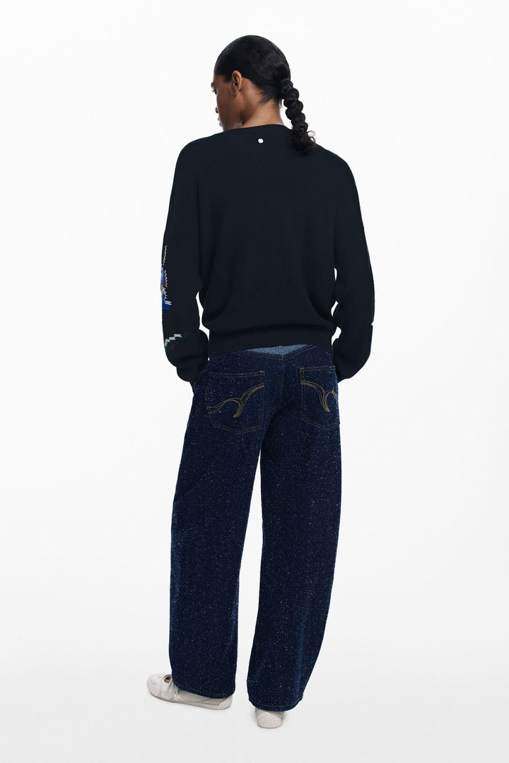 Homme portant un chandail à fleurs brodées et un jean ample vu de dos.