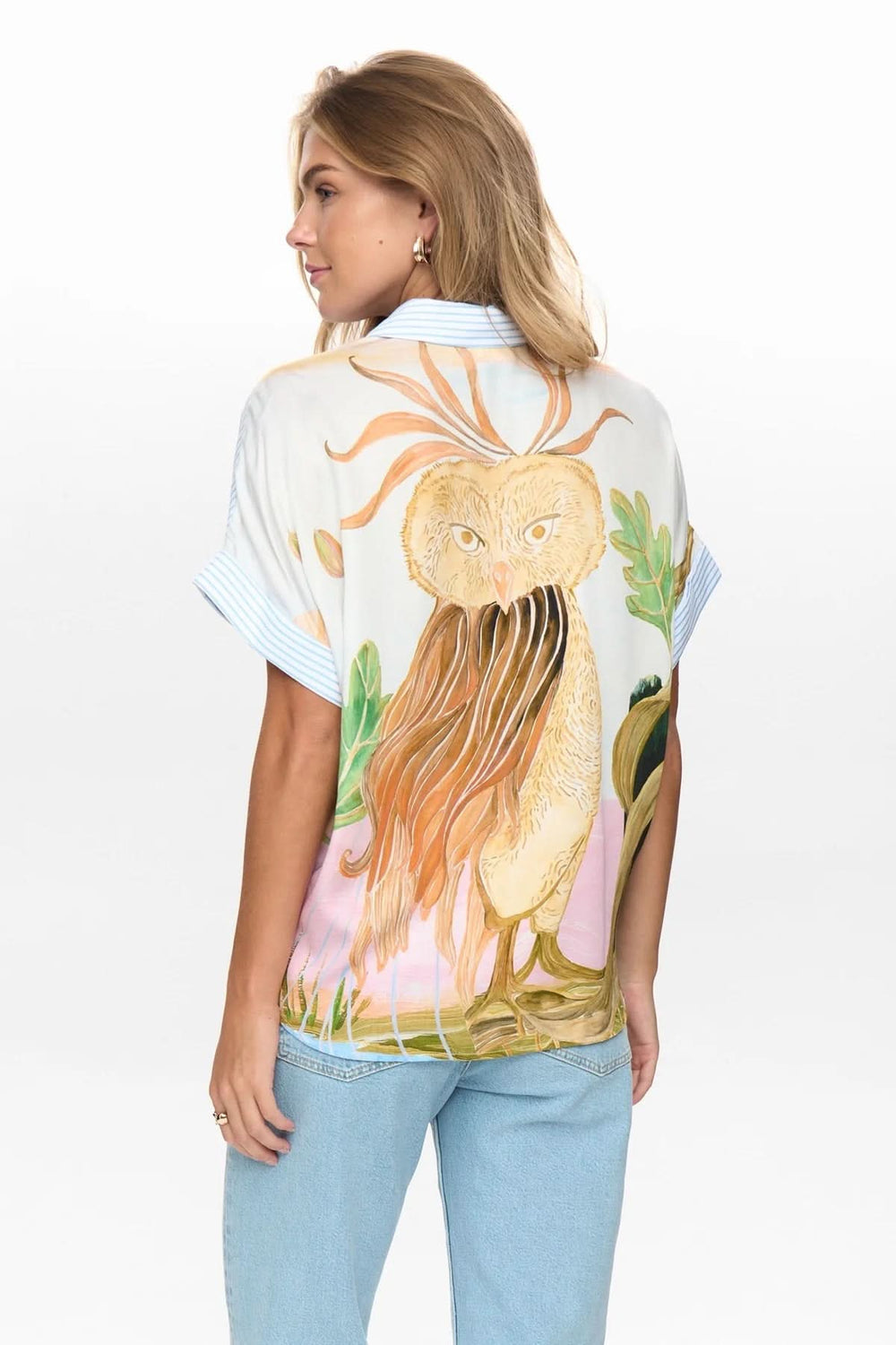 Femme portant chemise fluide à rayures avec imprimé artistique au dos, manches courtes et coupe ample, dos visible.