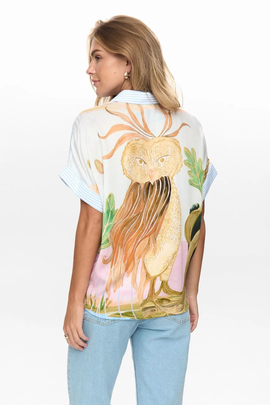 Femme portant chemise fluide à rayures avec imprimé artistique au dos, manches courtes et coupe ample, dos visible.