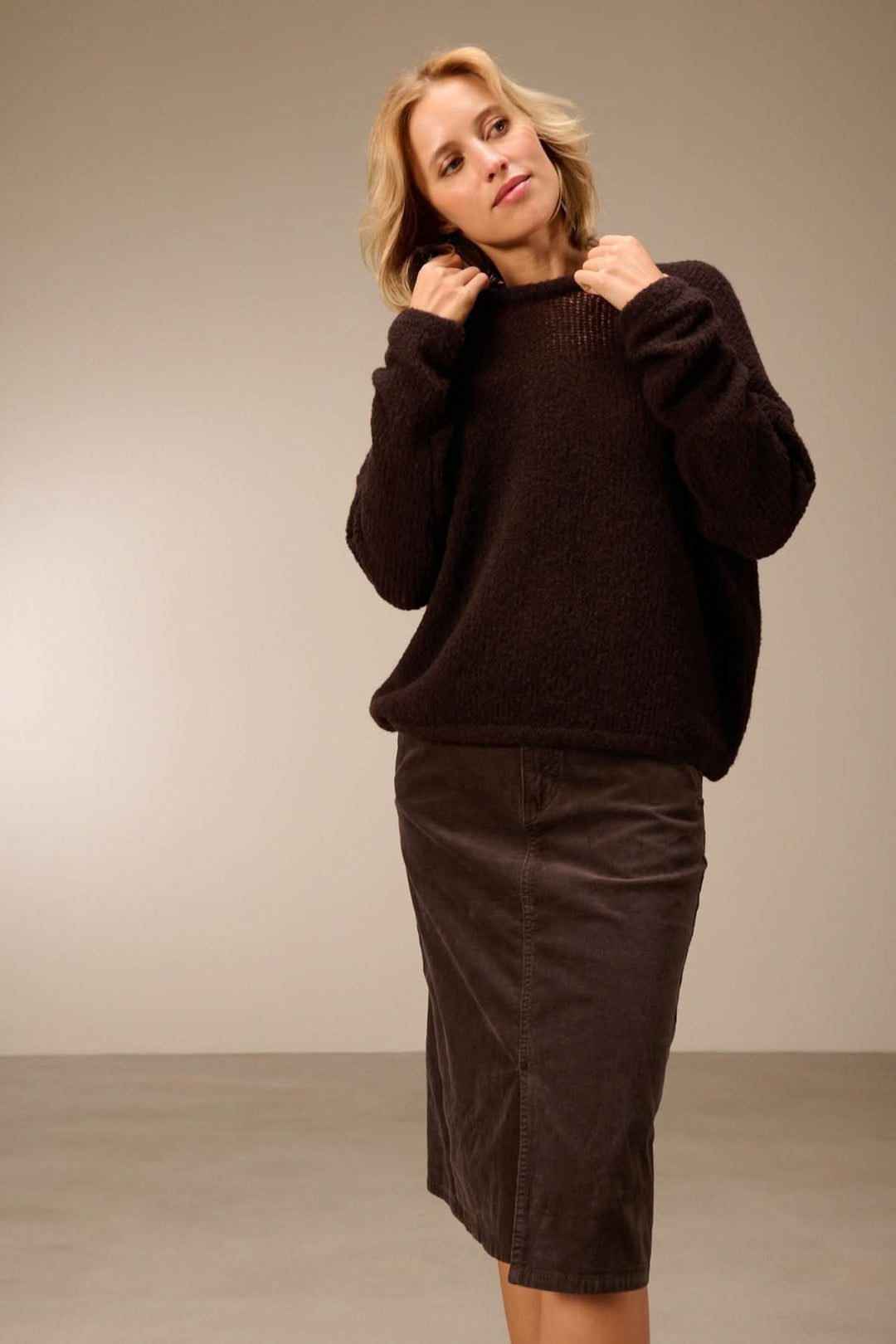 Femme portant un chandail ample en laine mérinos texturée avec une jupe pour un look moderne et polyvalent.