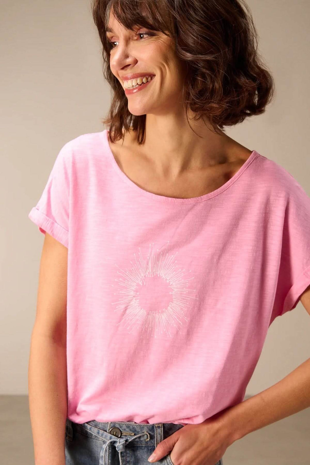 Femme portant un T-shirt à manches courtes coupe décontractée rose, avec revers aux manches et encolure ronde.