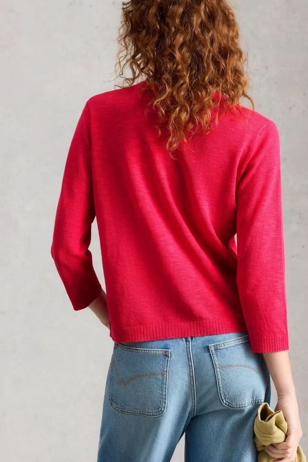 Femme portant un cardigan en maille à col v boutonné rouge, vue de dos avec manches longues et coupe droite.
