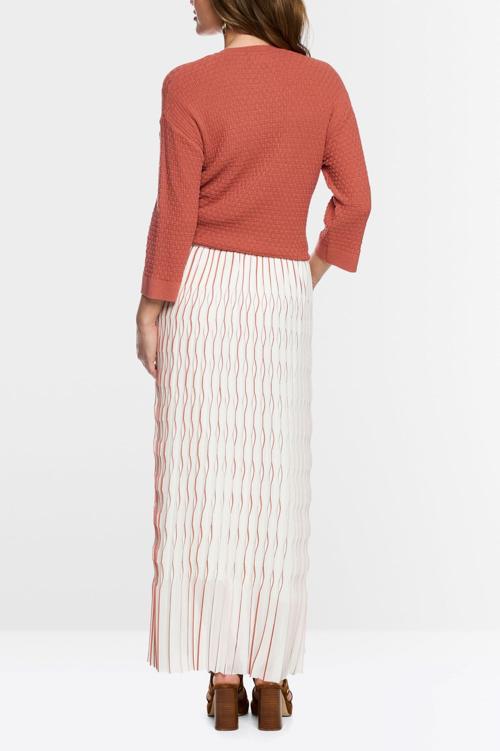 Femme portant une jupe longue plissée avec un haut orange, vue de dos, avec design plissé et taille élastique pour confort et élégance.