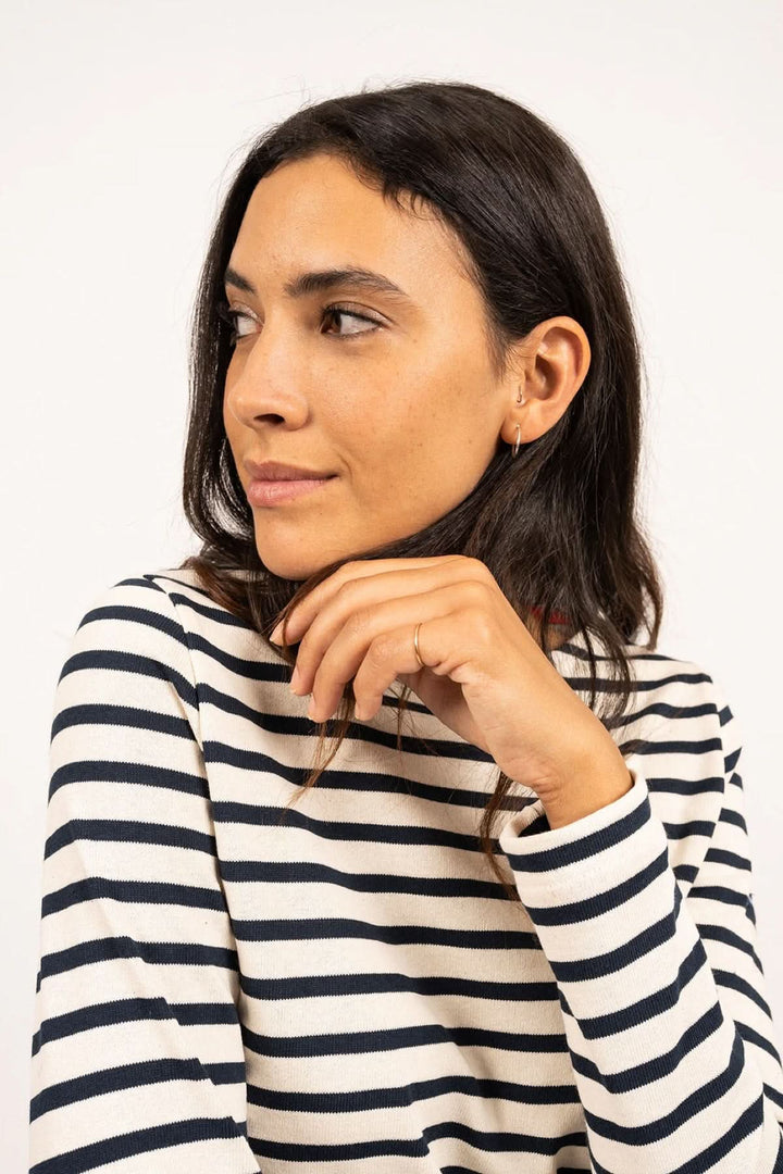 Femme portant un chandail marinière à rayures avec coudières en cœur, pour un style chic et décontracté.