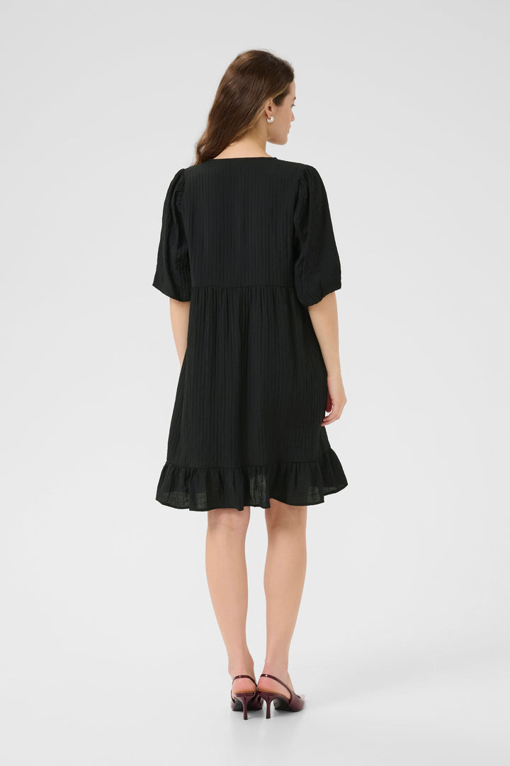 Robe courte Lianna vue de dos, en mousseline noire avec manches bouffantes et bas volanté.