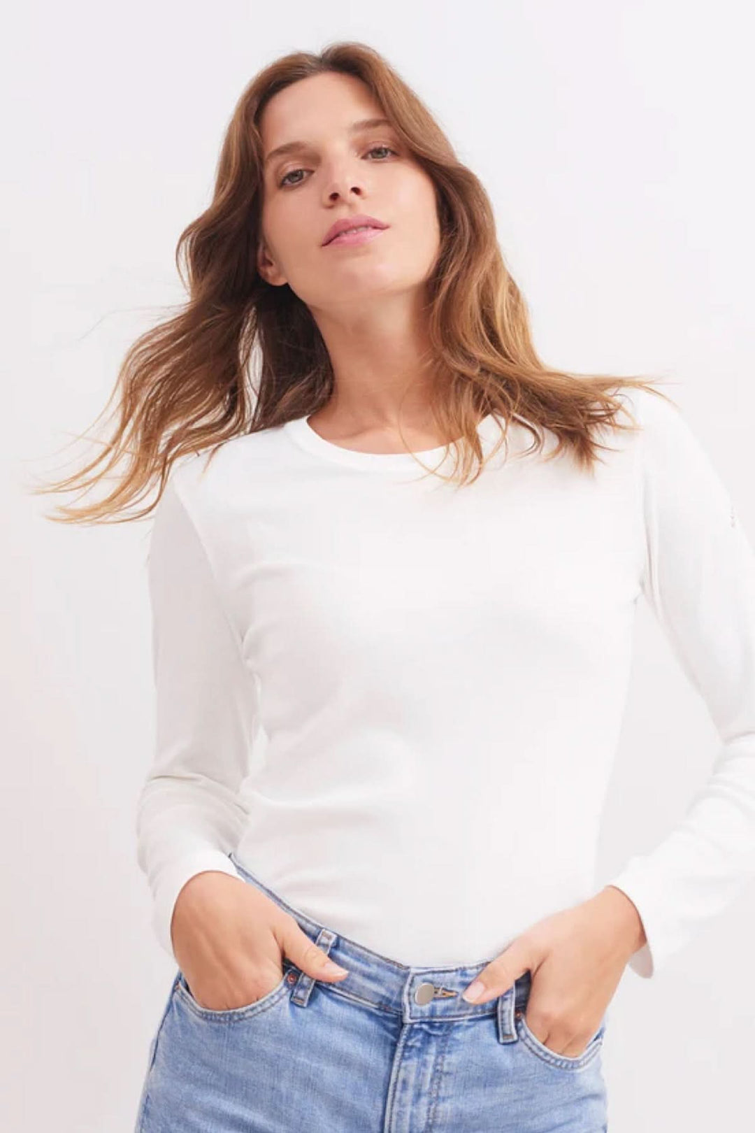 Chandail à manches longues blanc en jersey de coton, style épuré, porté avec un jean, look casual chic.
