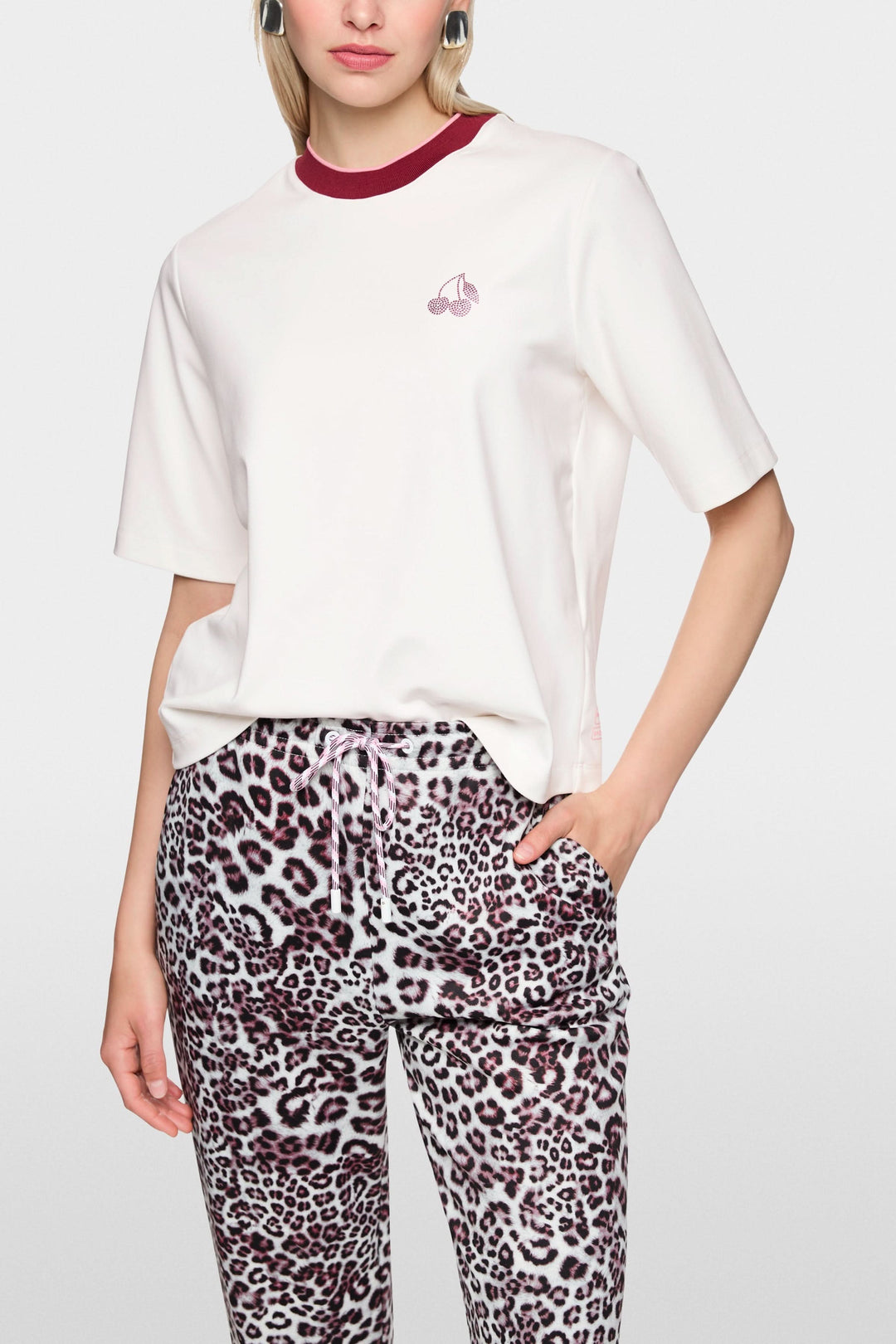 T-shirt classique blanc avec col contrasté porté par mannequin, logo Marc Cain Sport visible, manches courtes, style décontracté.