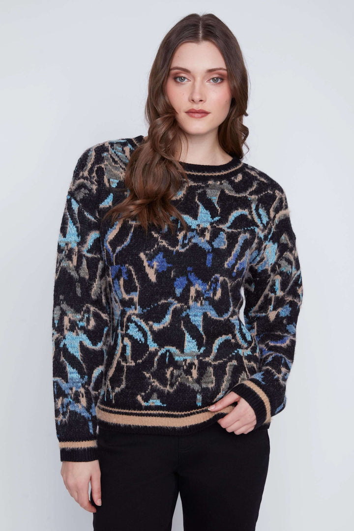 Tricot à manches longues avec motif abstrait multicolore, coupe droite et finition côtelée, porté avec pantalon noir.