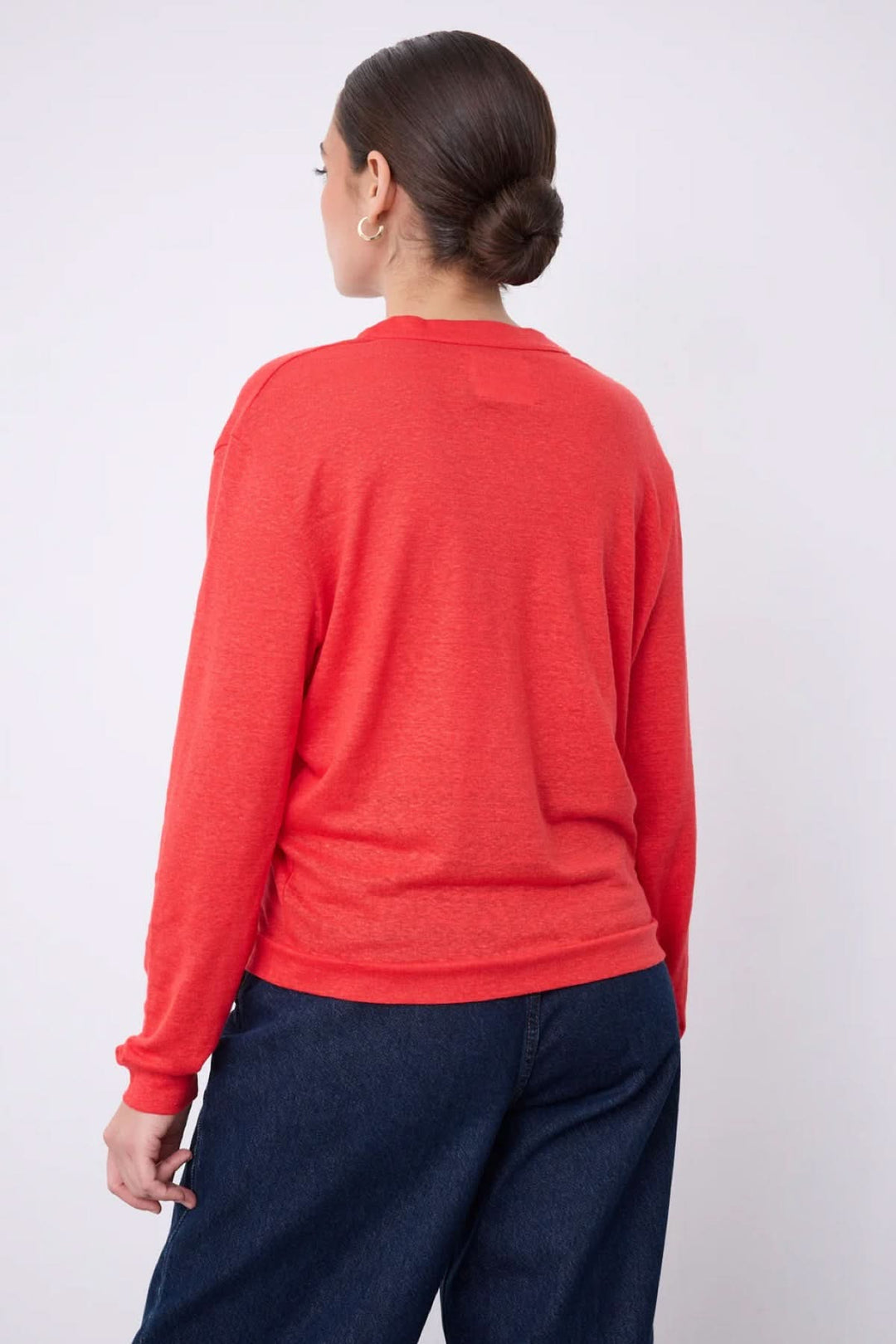 Vue arrière d'une femme portant un cardigan col v boutonné léger rouge, avec manches longues et coupe fluide.