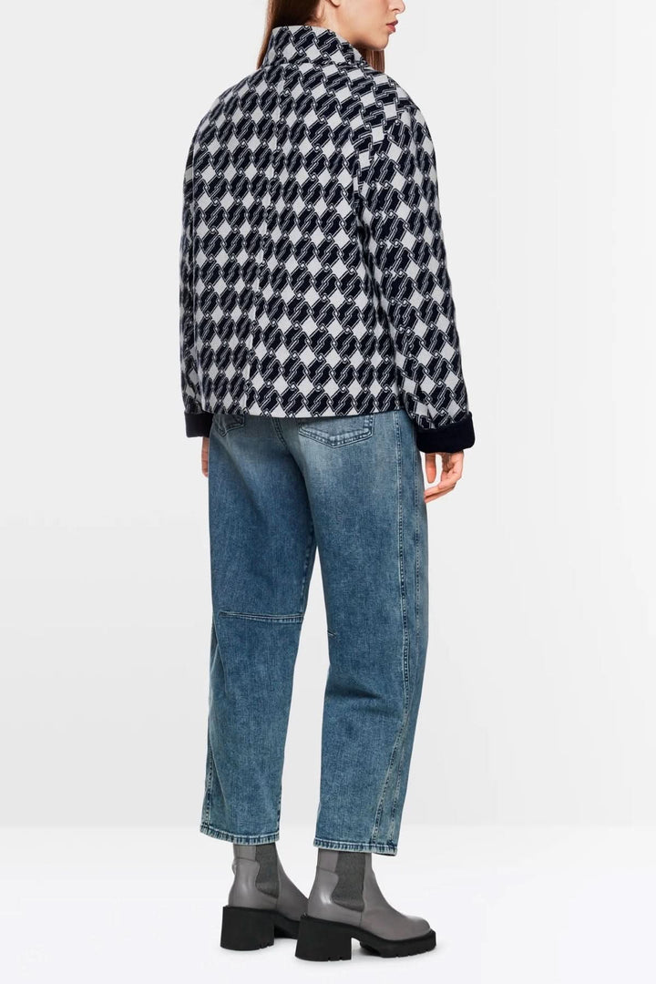Veste à motif graphique avec imprimé géométrique, portée avec un pantalon denim et des bottes, vue arrière.