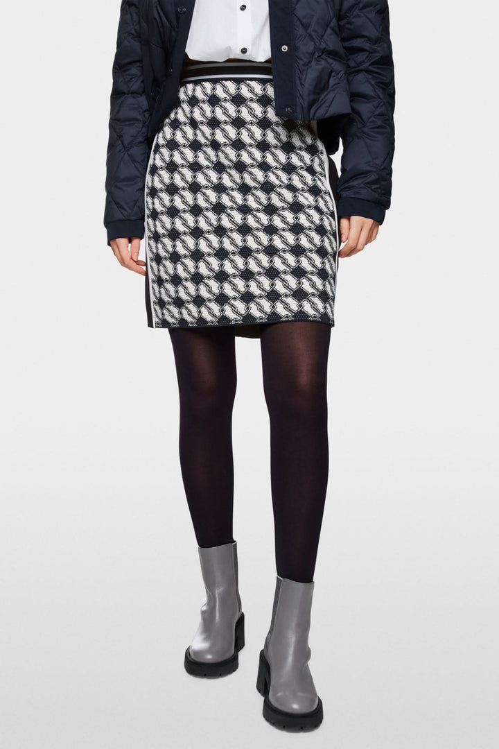 Jupe en maille à motif cubique, taille élastique, portée avec des chaussettes noires et des bottines grises.