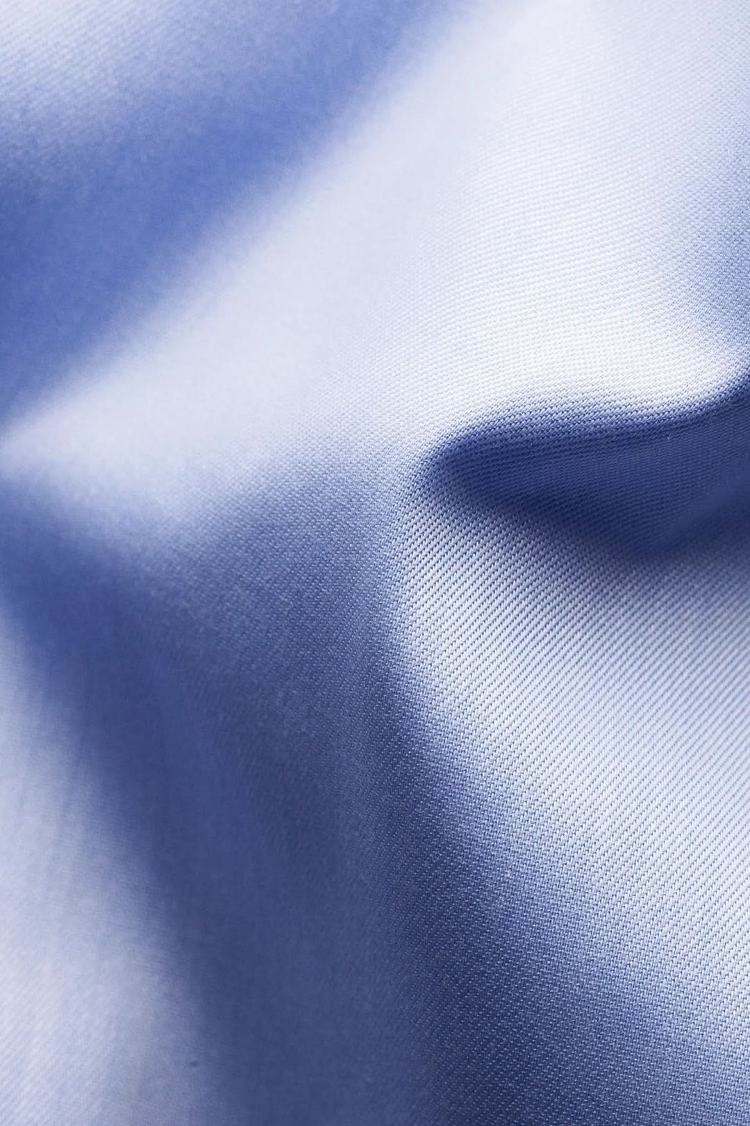Texture de coton doux d'une chemise en coton signature à col italien, vue en gros plan, montrant le tissu bleu lisse et élégant.