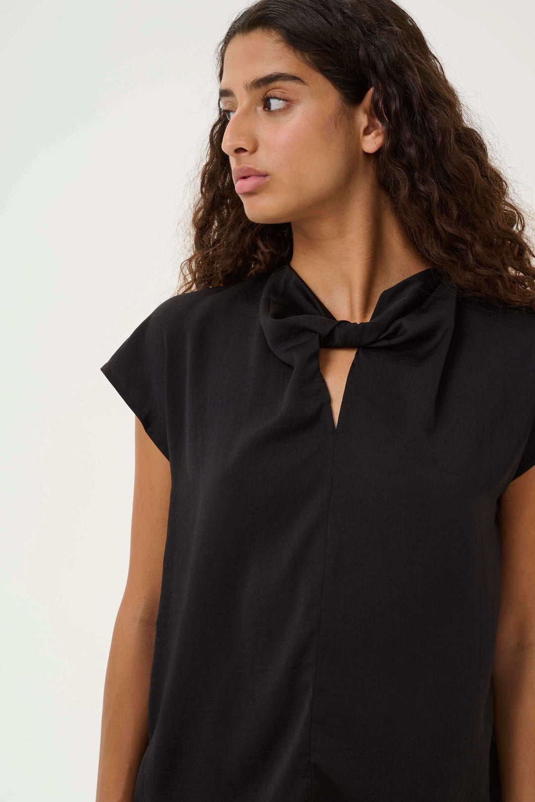Blouse Danni fluide à col nœud avec manches courtes et coupe décontractée en noir, idéale pour un look élégant et confortable.